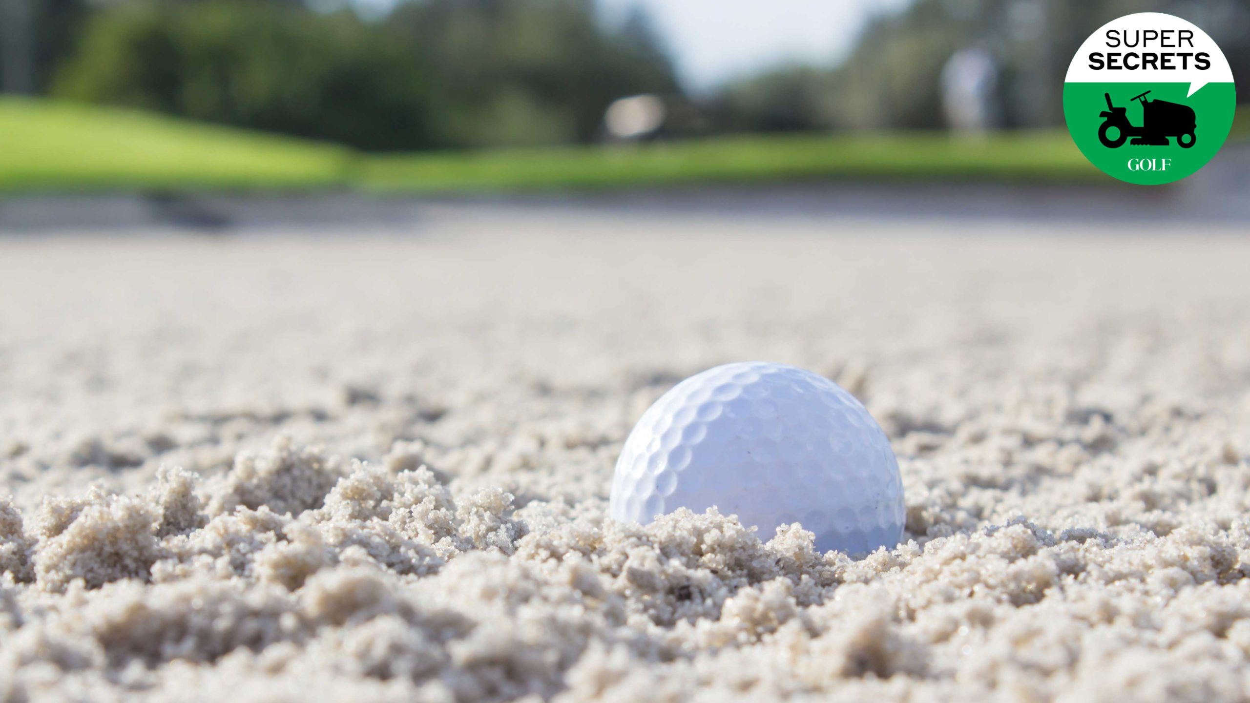 golf ball sits in sand bunker on golf course