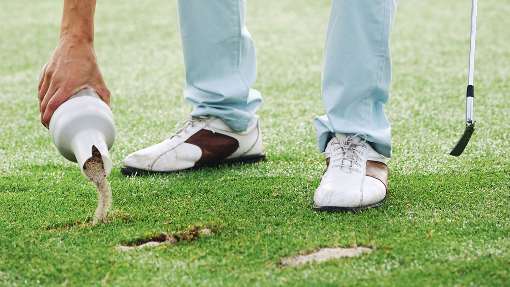 golfer using sand to fill divot