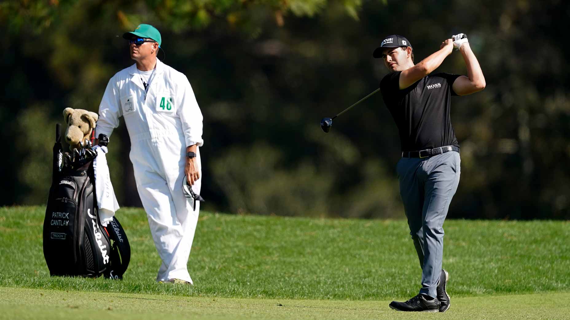 patrick cantlay swings as caddie looks on