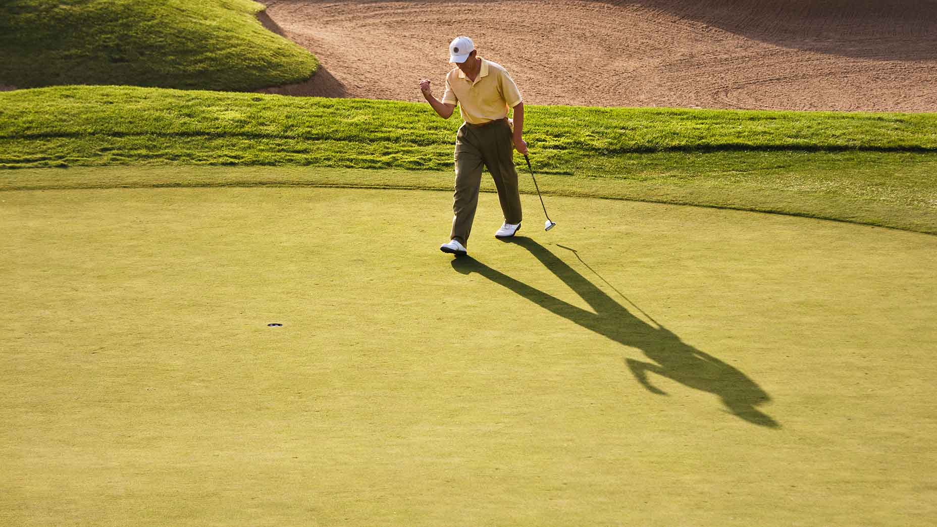 A golfer pumps their fist on the green.