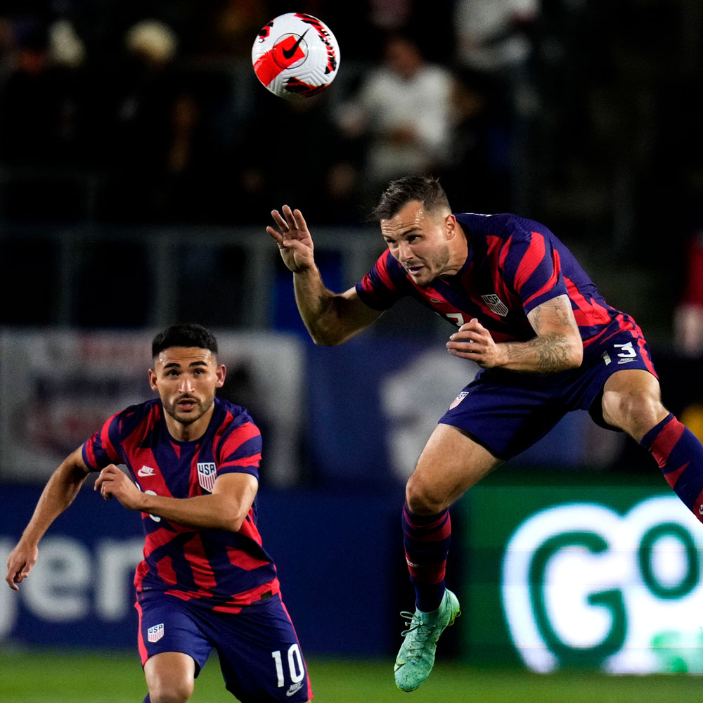 Jordan Morris gets a head on the ball playing for Team USA, with Cristian Roldan looking on.