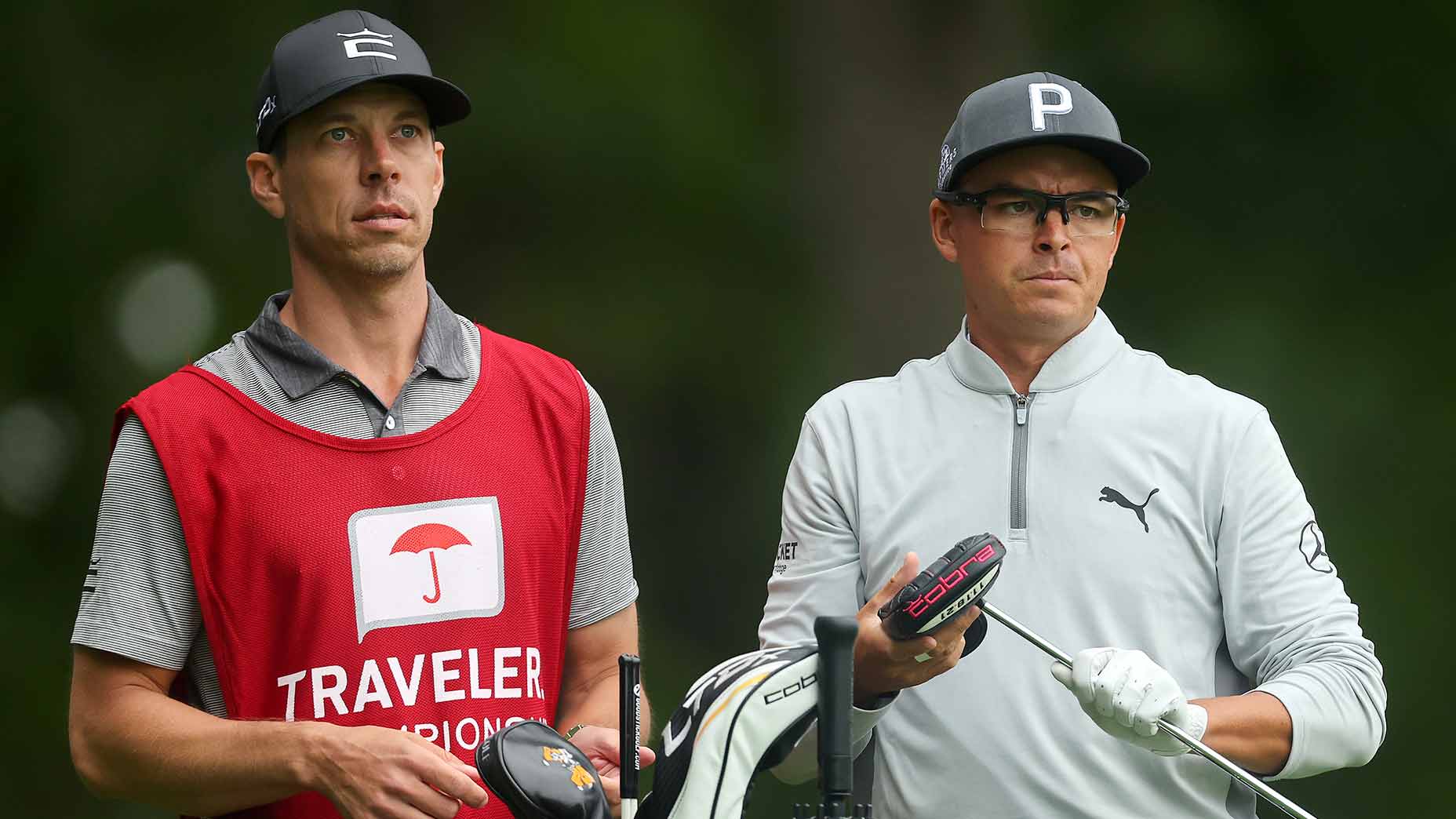 Rickie Fowler and caddie Joe Skovron look over a shot