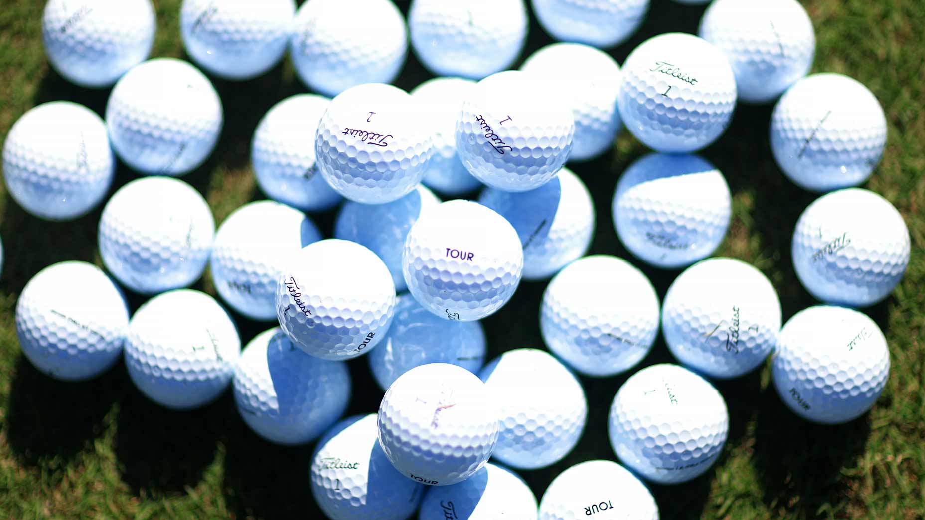 A detail shot of golf balls on a practice range.