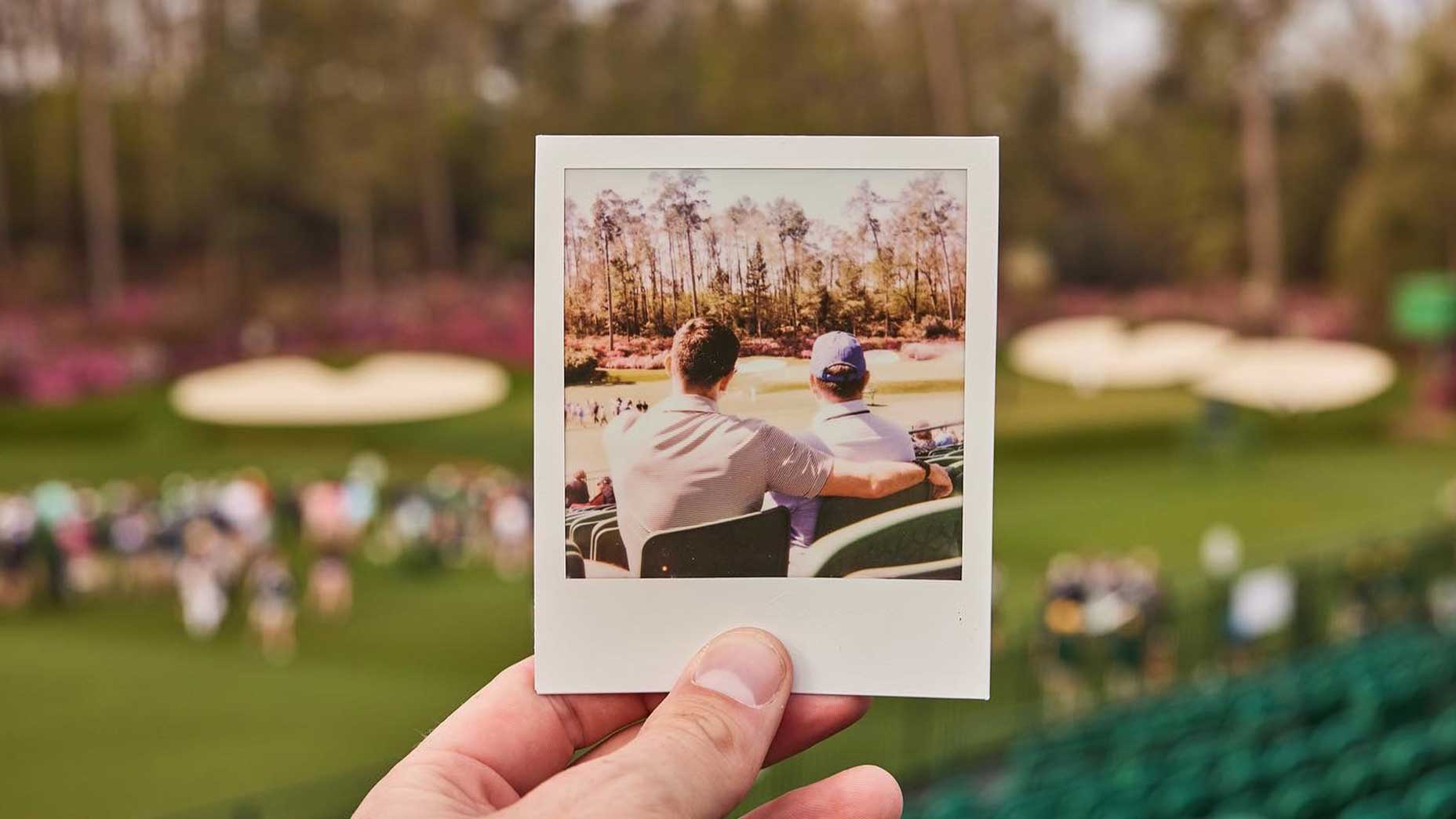 a man sits with his arm around another man's shoulder at Augusta National.