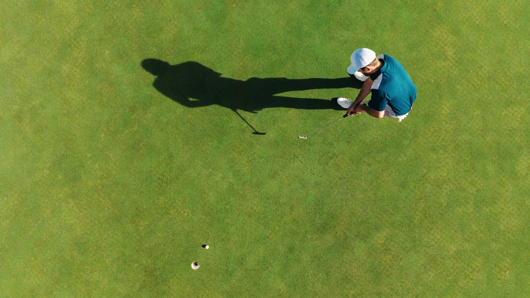 Golfer putting on green from above.