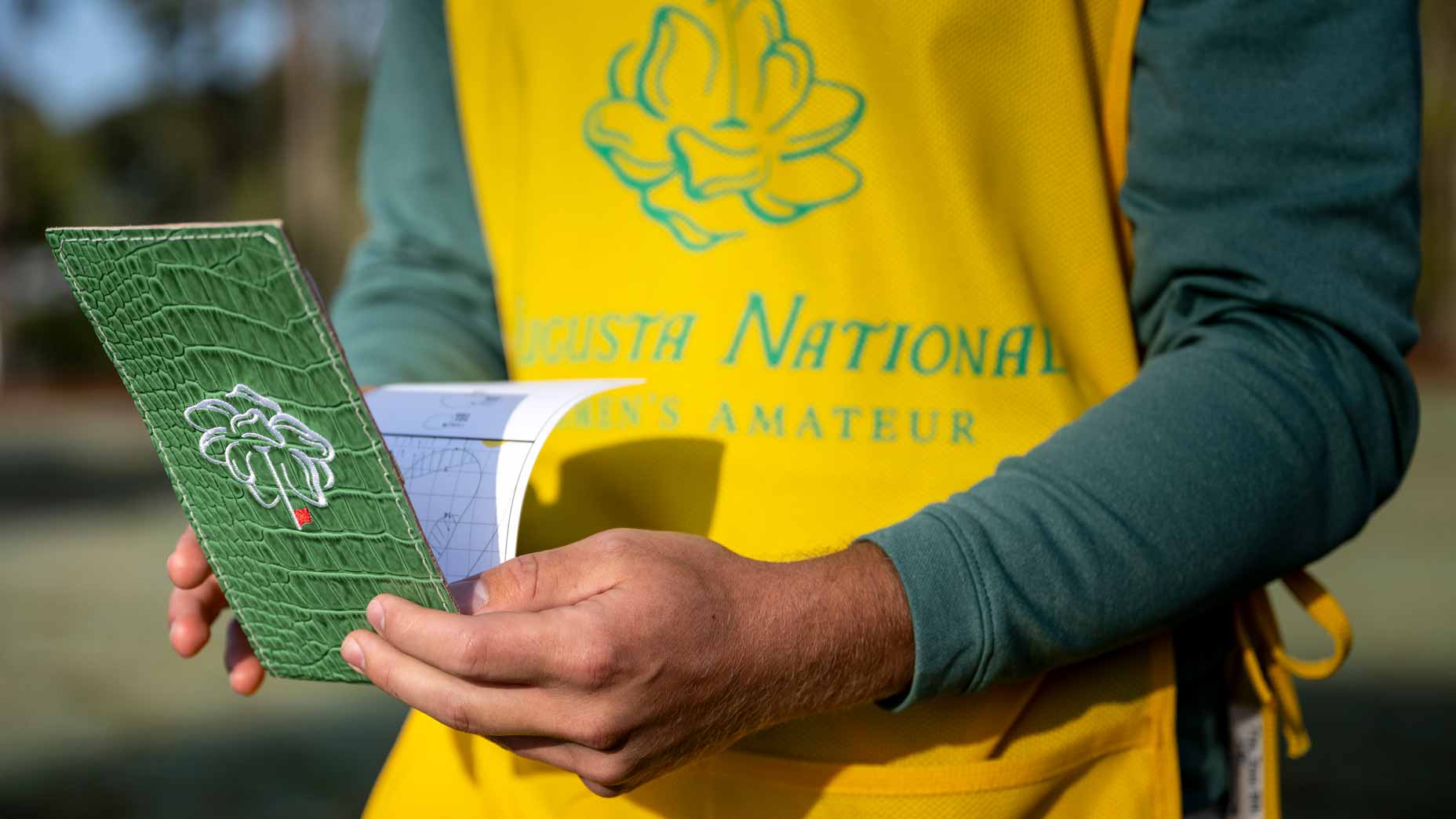 Augusta National Women's Amateur caddie reads a yardage book at Champions Retreat Golf Club.