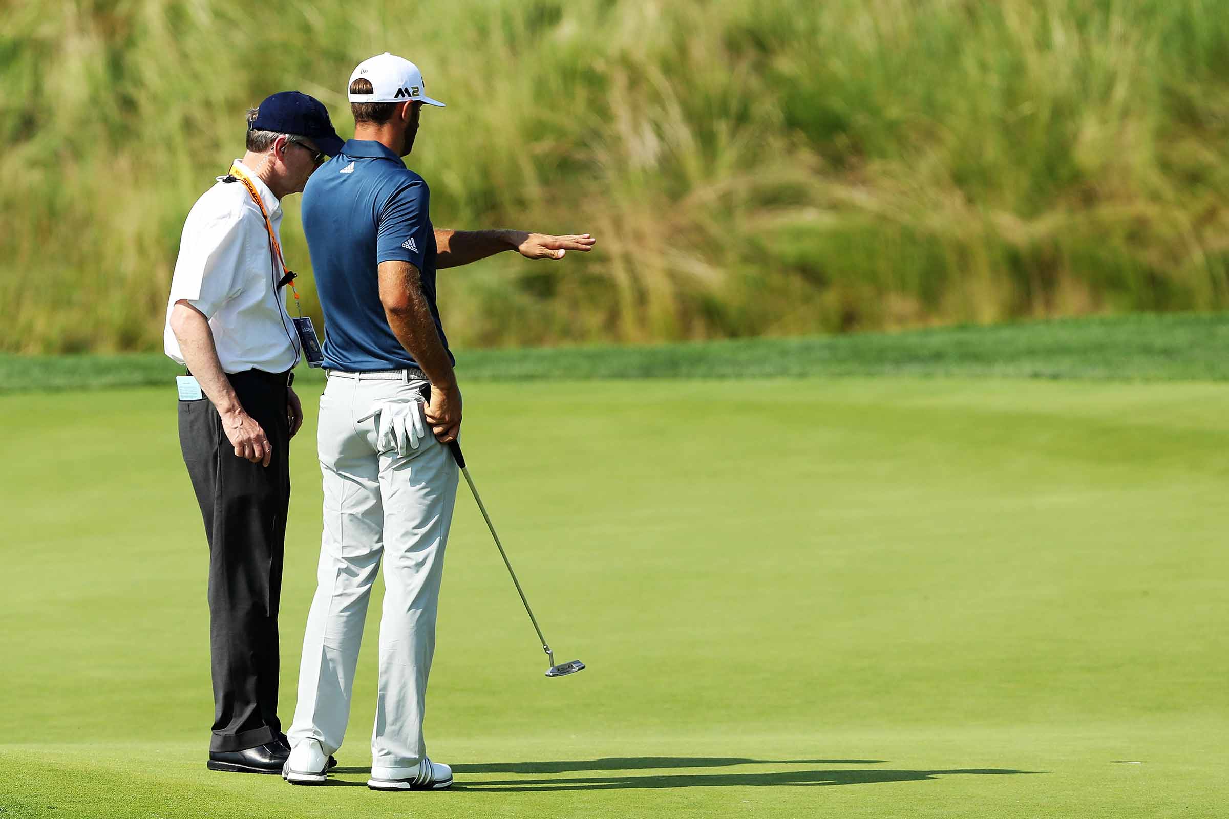 Dustin Johnson speaks with rules official Mark Newell on the 5th green during the final round of the 2016 U.S. Open at Oakmont.