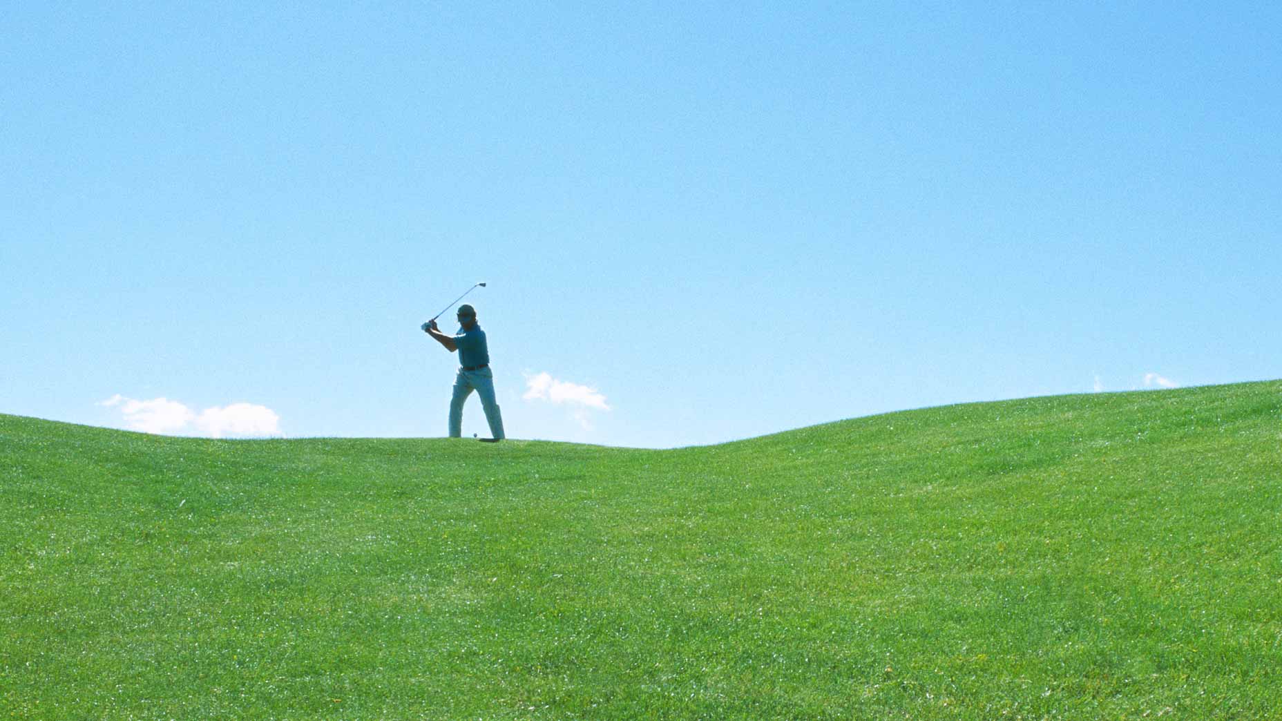 Golfer hits shots on golf course in distance