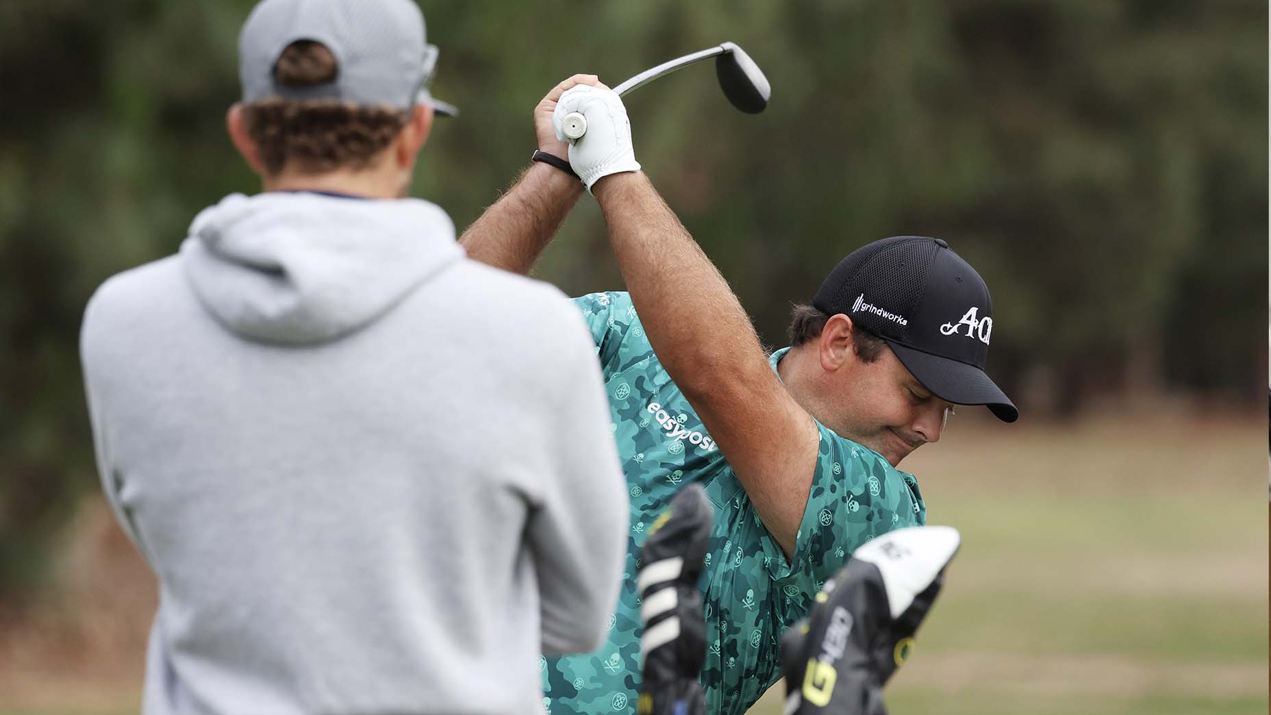 Patrick Reed of the United States hits on the range as his caddie Kessler Karain looks on during a practice round prior to the 123rd U.S. Open Championship at The Los Angeles Country Club on June 13, 2023 in Los Angeles, California.